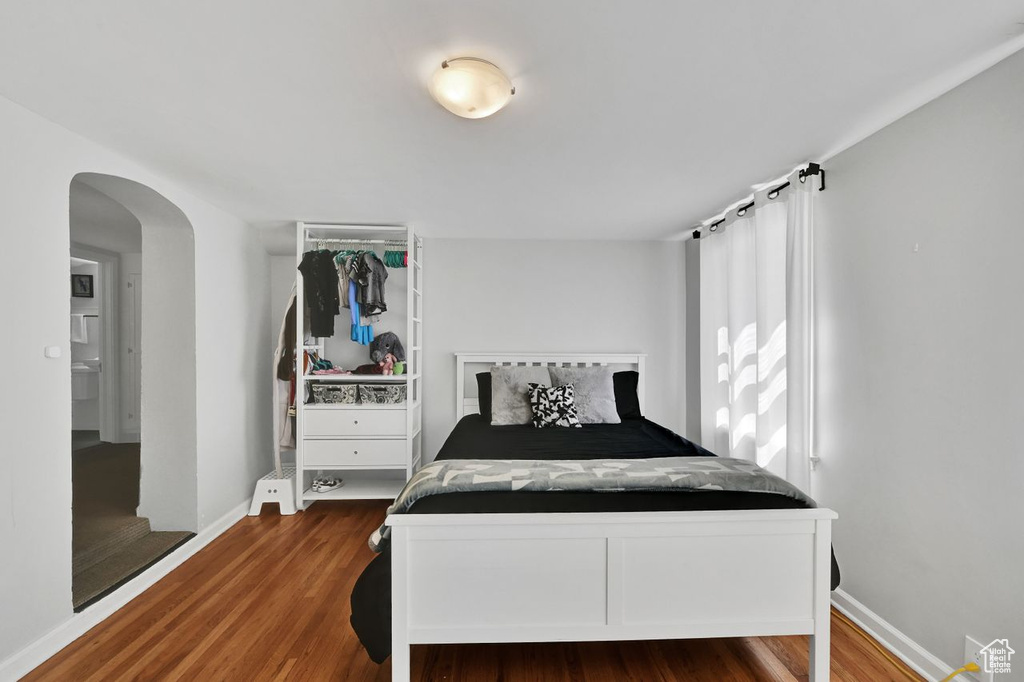 Bedroom with arched walkways, baseboards, and wood finished floors