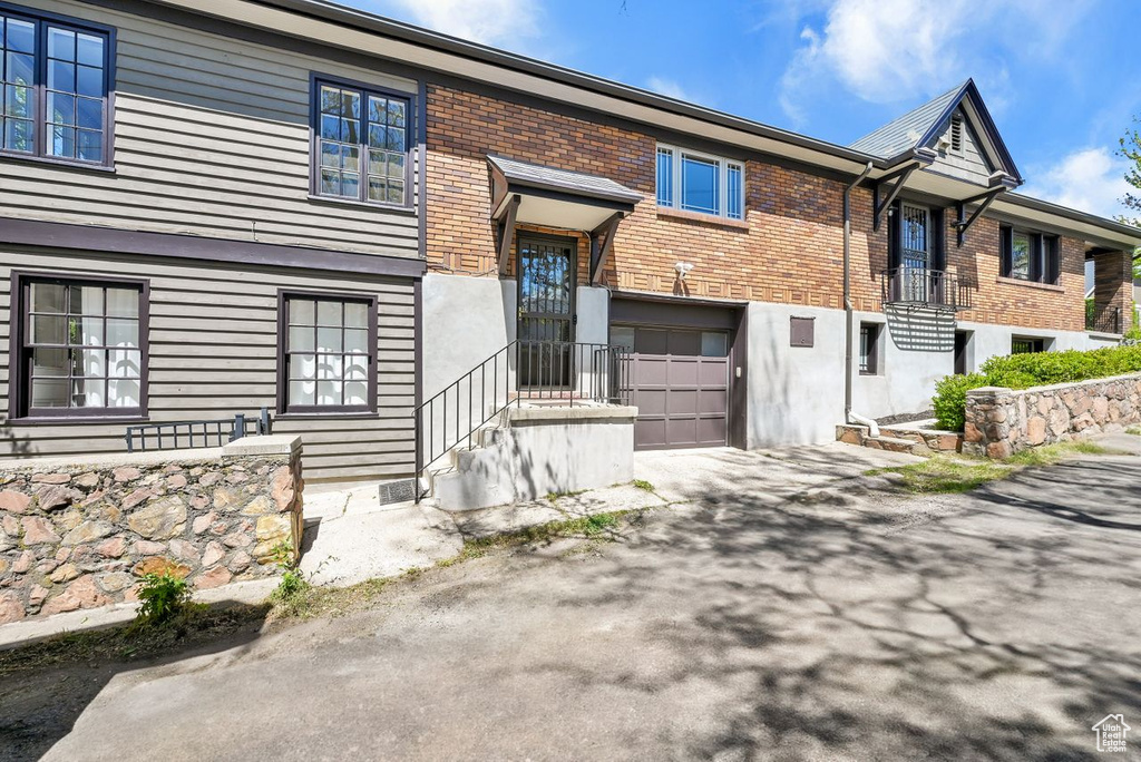 View of front facade featuring brick siding, aphalt driveway, and a garage