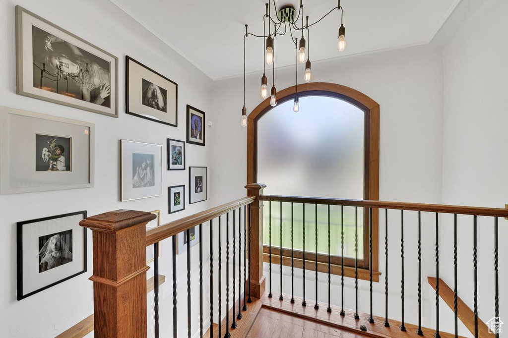 Corridor featuring an upstairs landing, wood finished floors, and an inviting chandelier