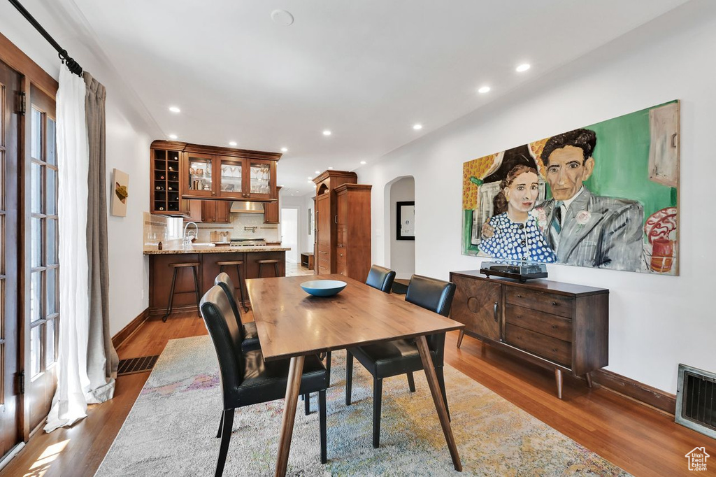 Dining room featuring visible vents, arched walkways, wood finished floors, and recessed lighting