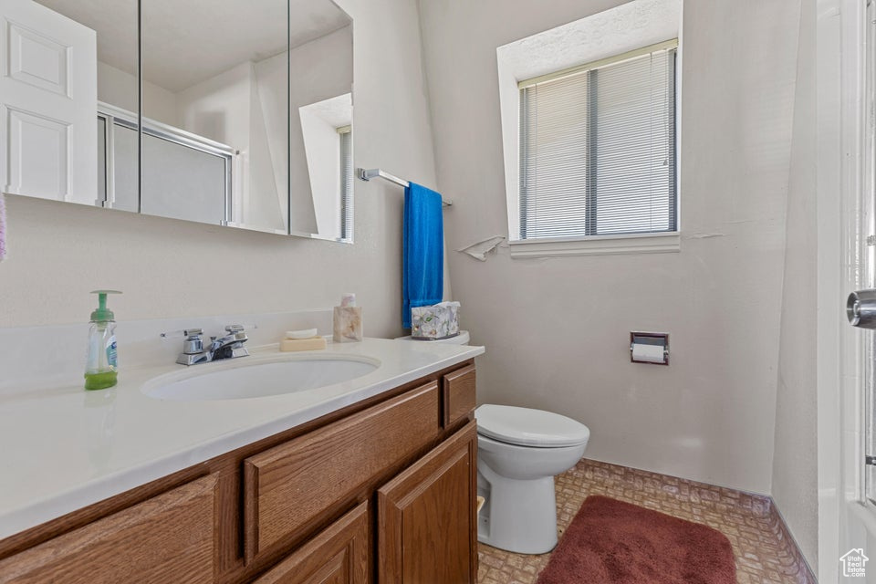 Bathroom featuring vanity, a shower with door, and toilet