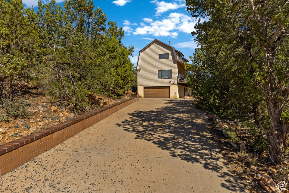 View of home's exterior featuring concrete driveway, a garage, and a gambrel roof
