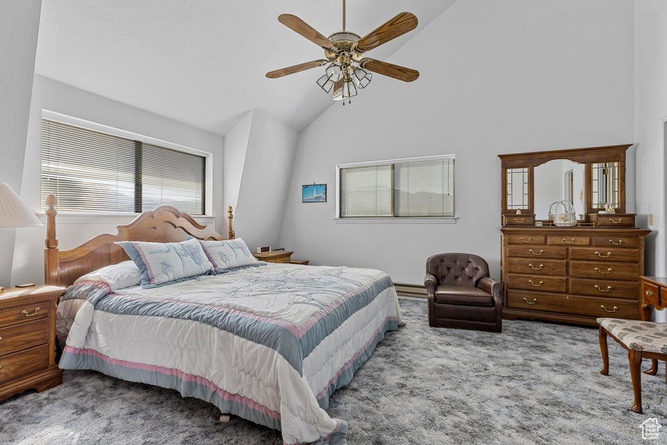 Carpeted bedroom with high vaulted ceiling, baseboard heating, and a ceiling fan