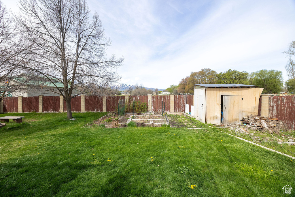 View of yard with a fenced backyard, an outbuilding, a vegetable garden, and a shed