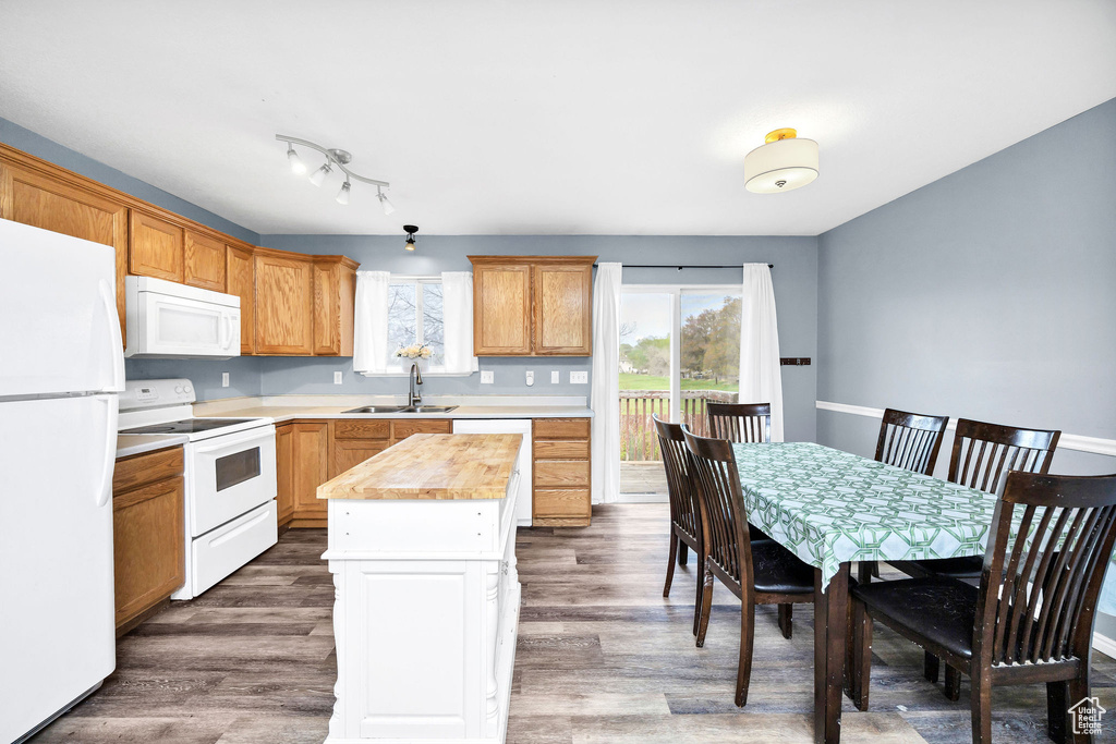 Kitchen featuring a sink, wood finished floors, a kitchen island, and white appliances