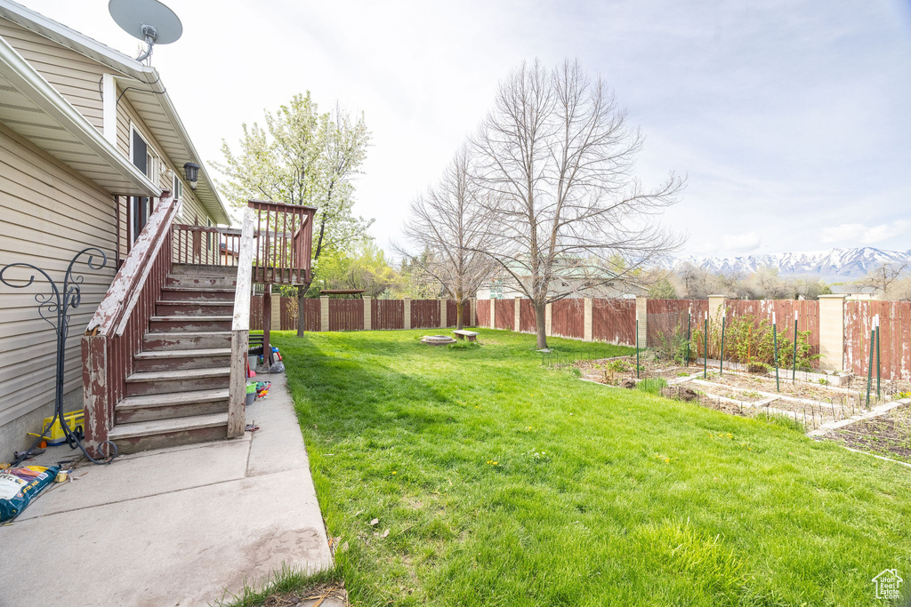 View of yard with a deck, a vegetable garden, a fenced backyard, and stairs