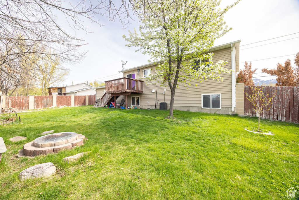 View of yard with stairs, a wooden deck, a fenced backyard, cooling unit, and a fire pit