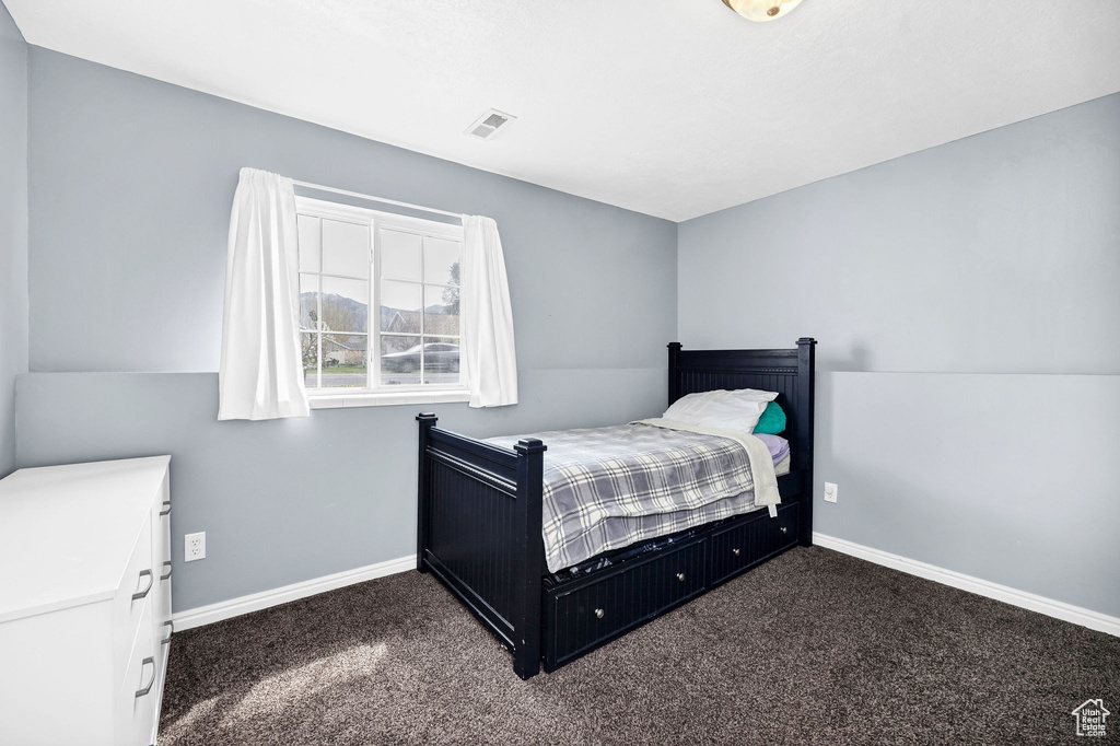 Bedroom featuring baseboards, dark carpet, and visible vents