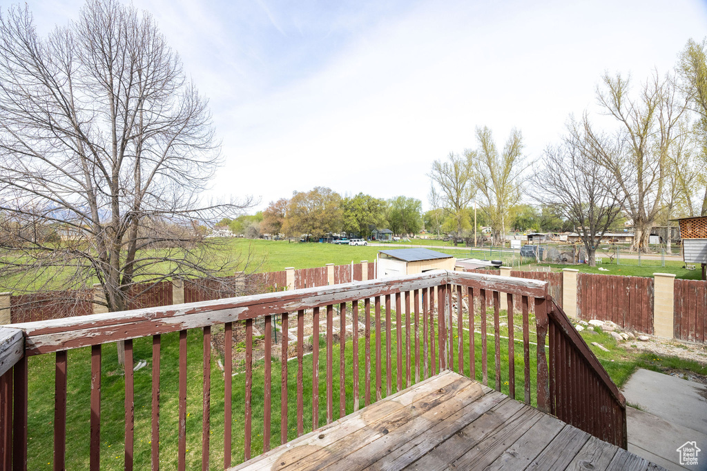 Deck with a fenced backyard, an outdoor structure, a yard, and a shed