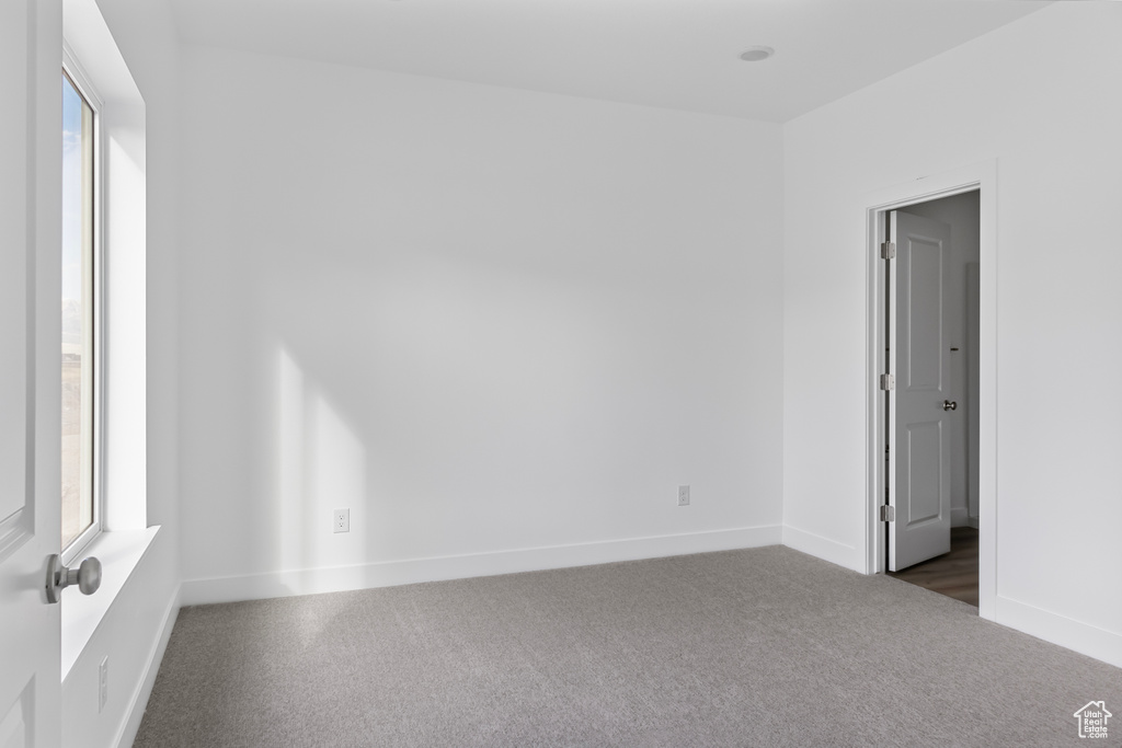 Unfurnished room with baseboards and dark colored carpet