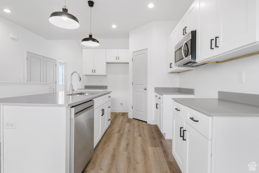 Kitchen with light wood finished floors, recessed lighting, a sink, stainless steel appliances, and pendant lighting