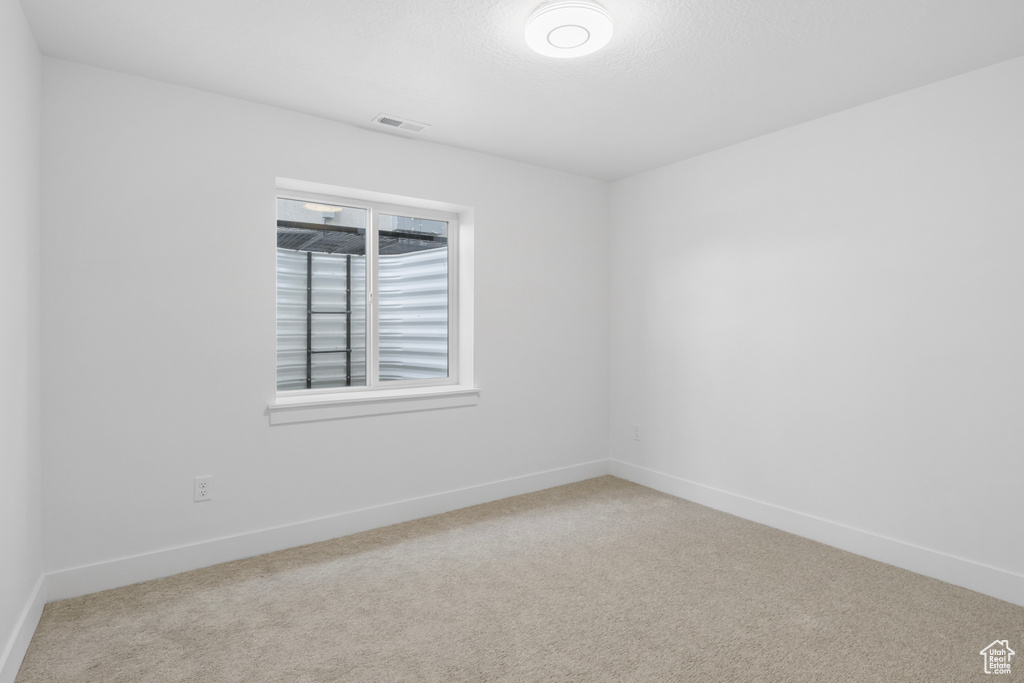 Spare room with baseboards, visible vents, and carpet flooring