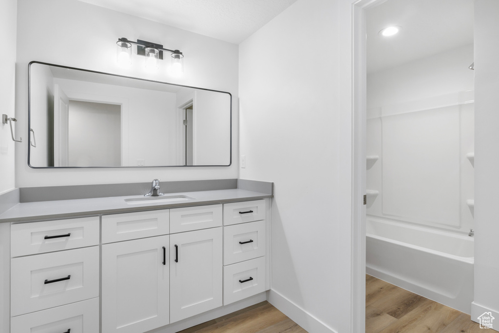 Bathroom featuring tub / shower combination, baseboards, recessed lighting, wood finished floors, and vanity