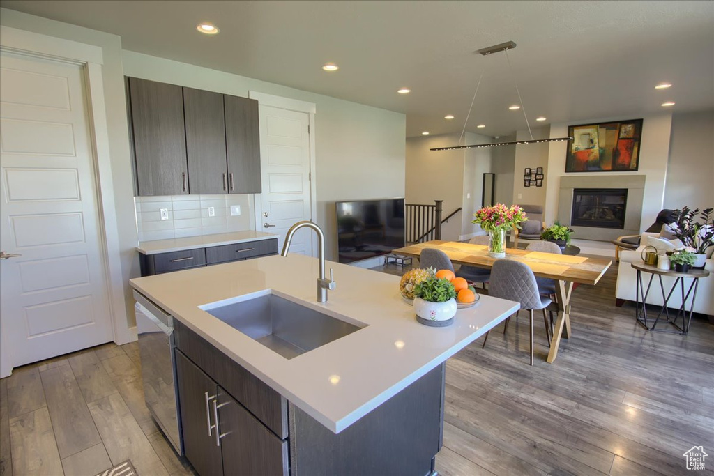 Kitchen with modern cabinets, stainless steel dishwasher, wood finished floors, a sink, and light countertops