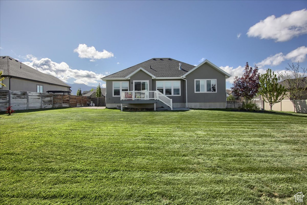 Rear view of house featuring a lawn, a fenced backyard, and a shingled roof