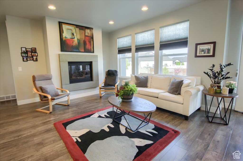 Living room with a glass covered fireplace, baseboards, recessed lighting, and wood finished floors