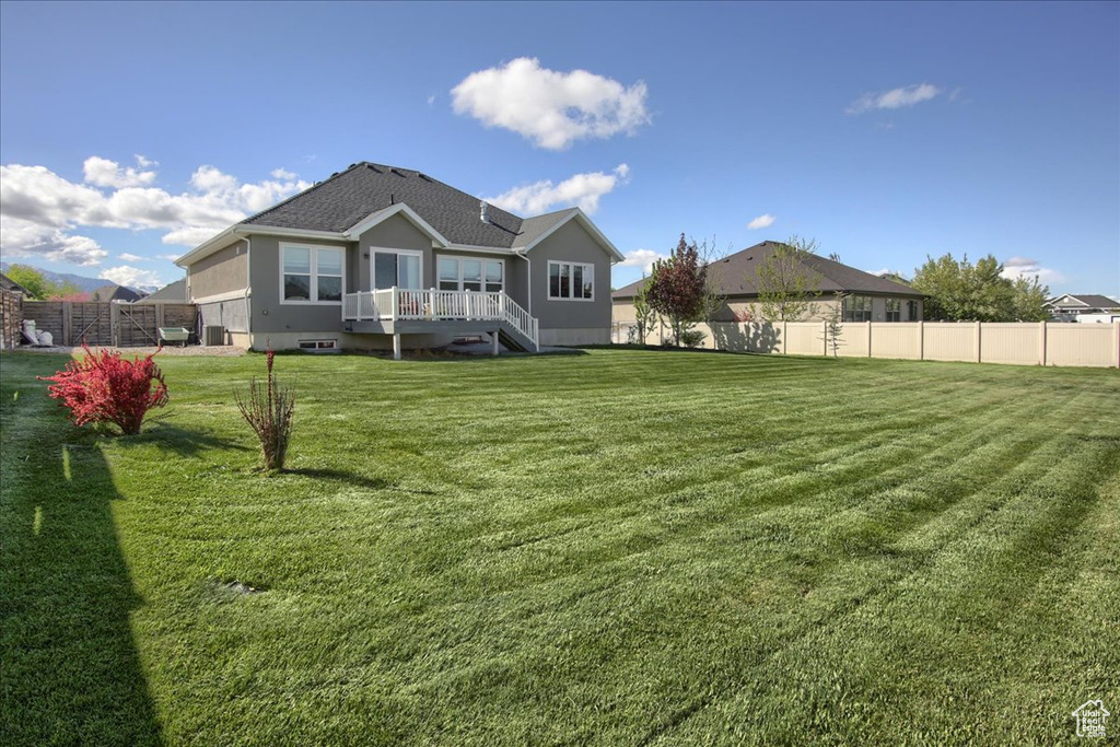Back of property featuring stucco siding, fence, and a yard