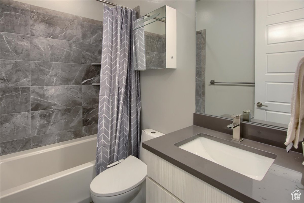 Full bathroom with vanity, shower / tub combo with curtain, and toilet