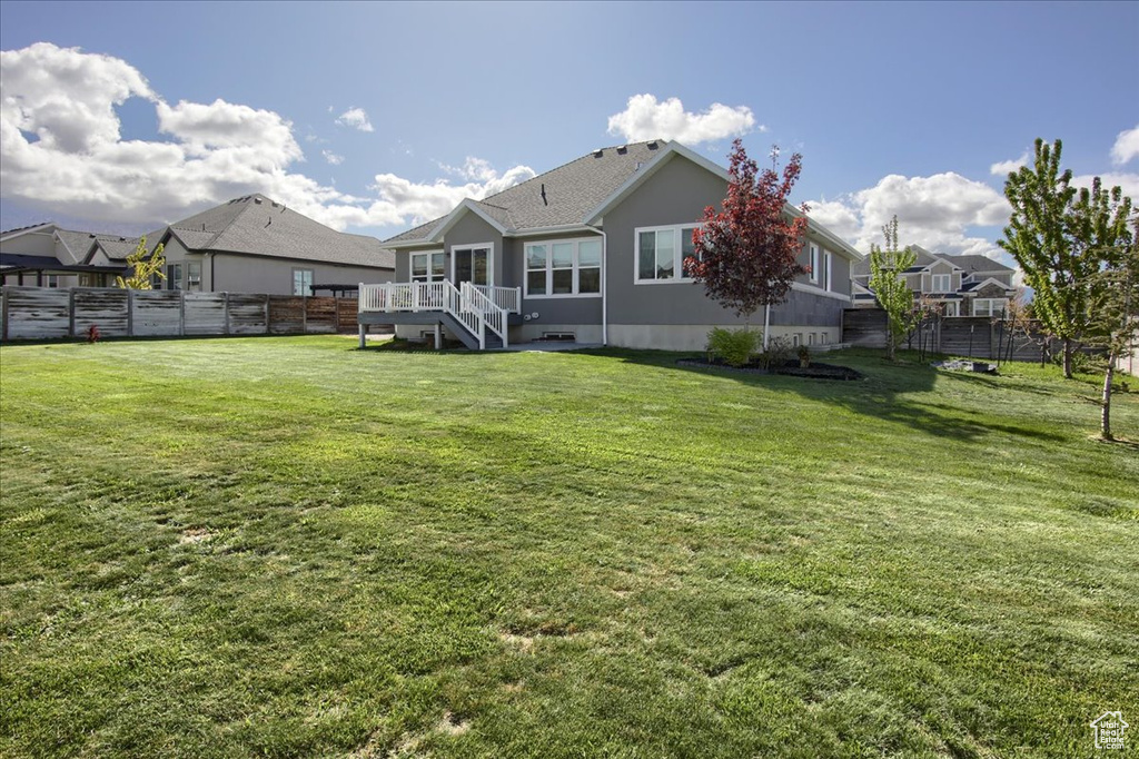 Rear view of property with a yard, fence, and stairs