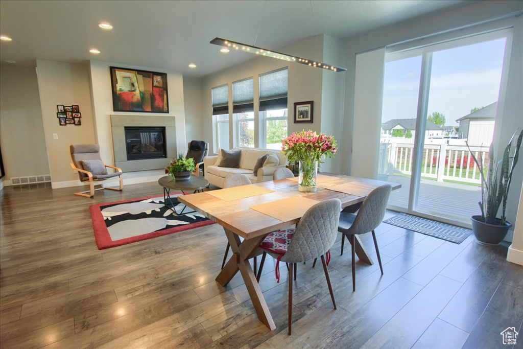 Dining space with recessed lighting, baseboards, a glass covered fireplace, and wood finished floors