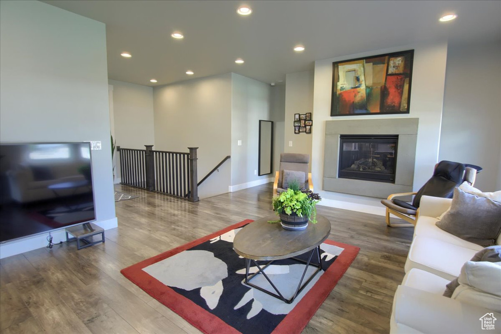 Living room with recessed lighting, a glass covered fireplace, and wood finished floors