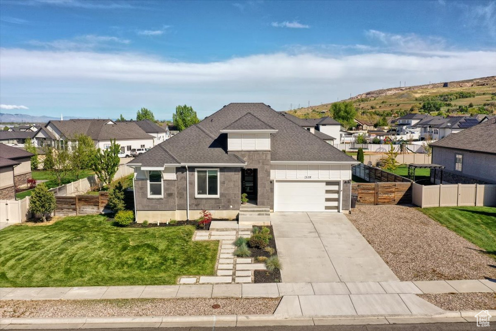 View of front of house with fence, stone siding, concrete driveway, an attached garage, and a residential view