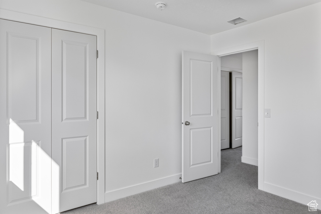 Unfurnished bedroom featuring baseboards and light carpet