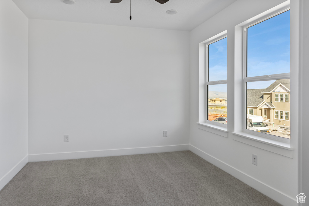 Unfurnished room featuring ceiling fan, carpet flooring, and baseboards