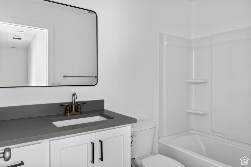 Bathroom featuring toilet,  shower combination, and vanity