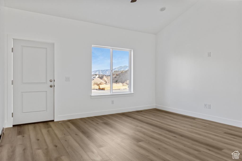 Spare room featuring ceiling fan, light wood-style flooring, and baseboards