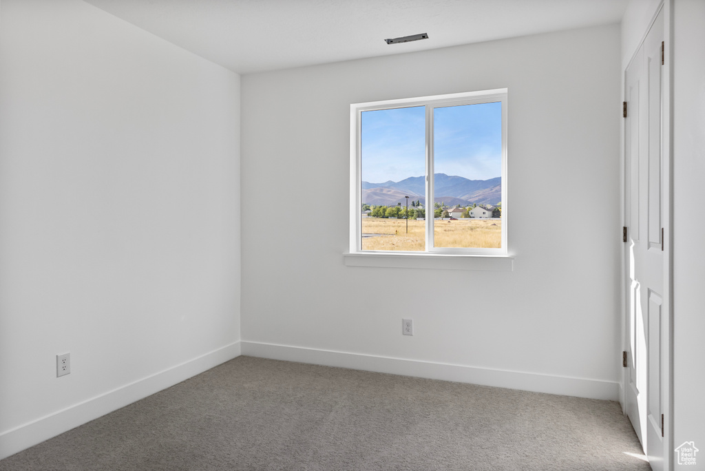 Unfurnished bedroom featuring a mountain view, baseboards, and carpet floors