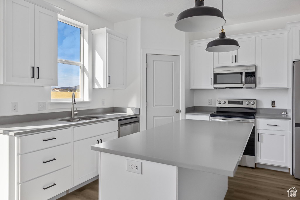 Kitchen with a sink, dark wood-style flooring, stainless steel appliances, a center island, and white cabinetry