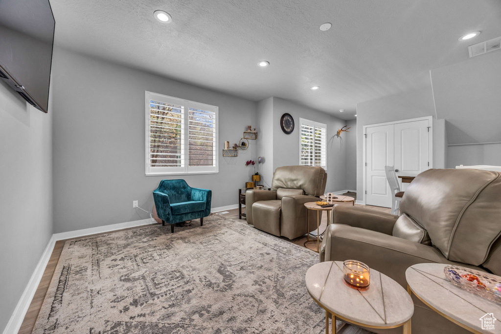 Living area with recessed lighting, baseboards, visible vents, and wood finished floors
