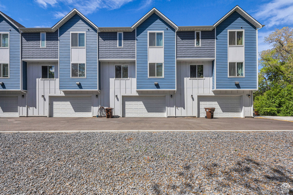 Multi unit property featuring a garage, board and batten siding, and aphalt driveway