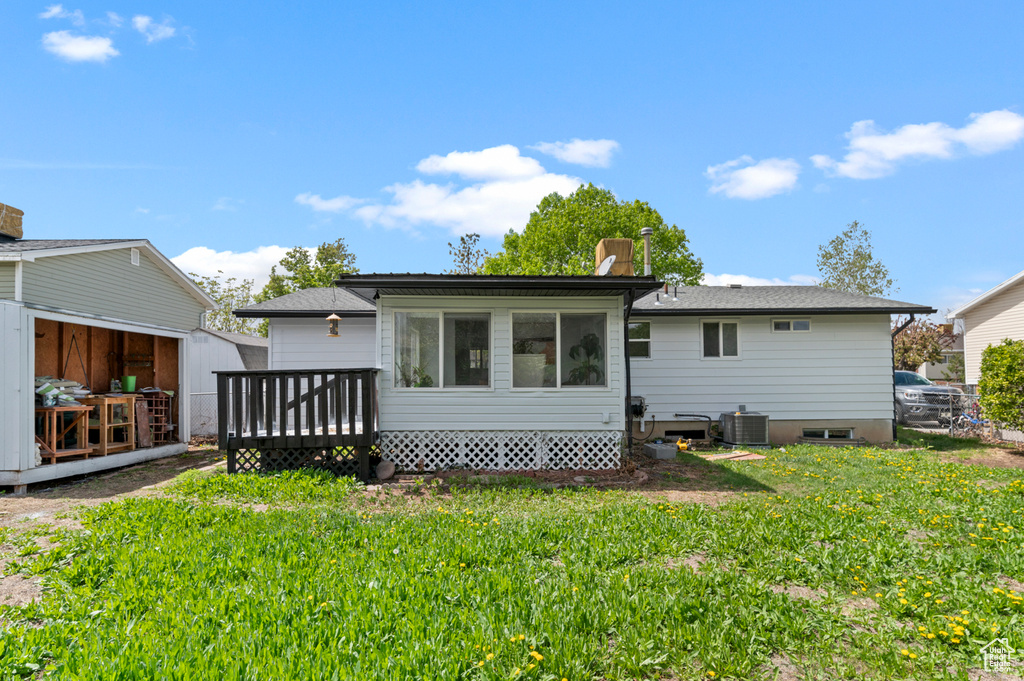 Rear view of house featuring a yard, a deck, central AC, and an outdoor structure