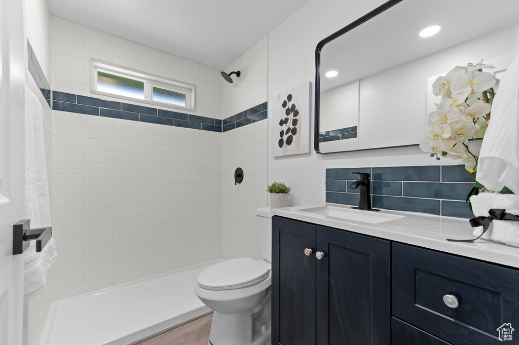 Full bath featuring toilet, tiled shower, and vanity