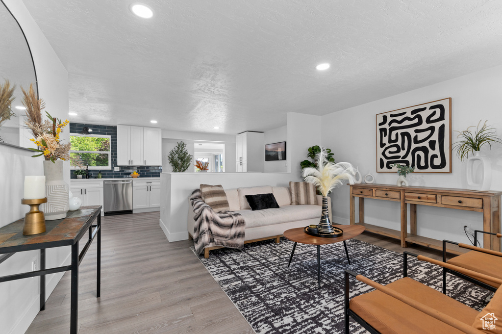 Living area with recessed lighting, a textured ceiling, and light wood-style flooring