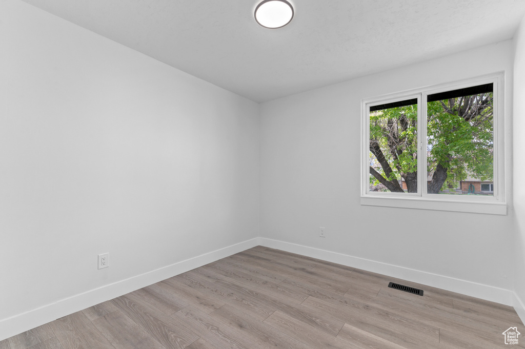 Unfurnished room with visible vents, baseboards, and light wood finished floors