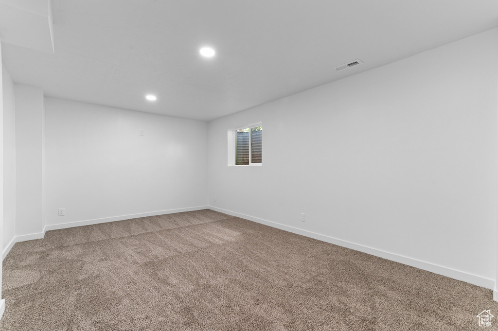 Carpeted spare room featuring baseboards, recessed lighting, and visible vents