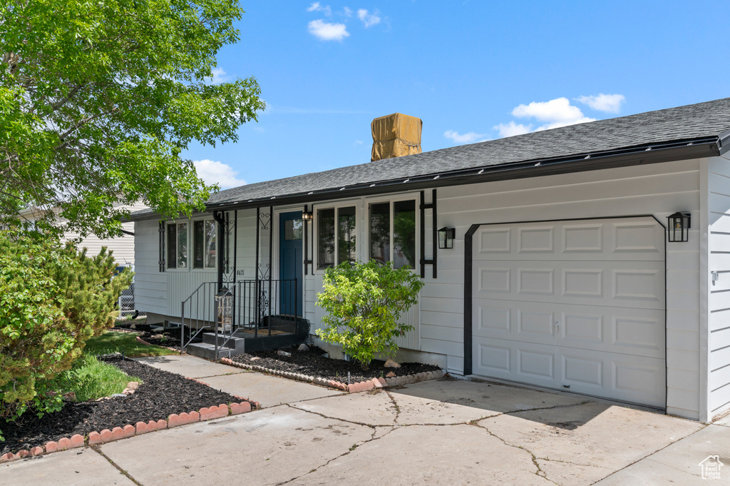 Ranch-style house featuring a garage, a shingled roof, and concrete driveway