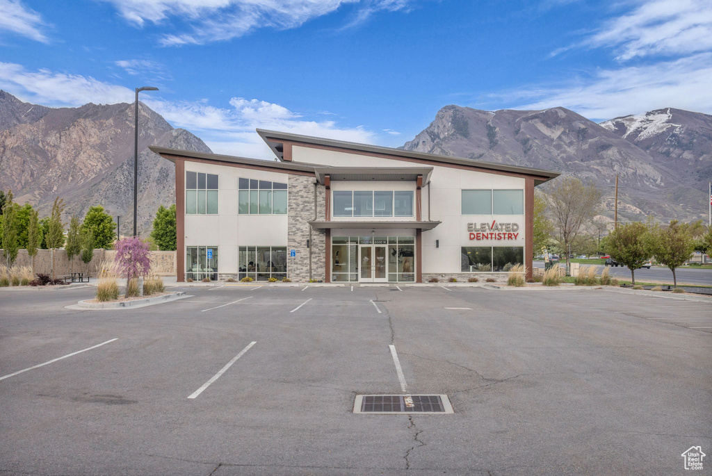 View of property with fence, uncovered parking, and a mountain view