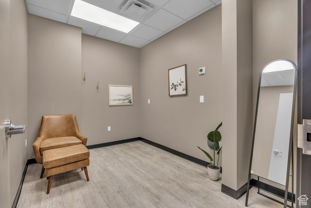 Living area with baseboards, visible vents, a drop ceiling, and light wood-type flooring