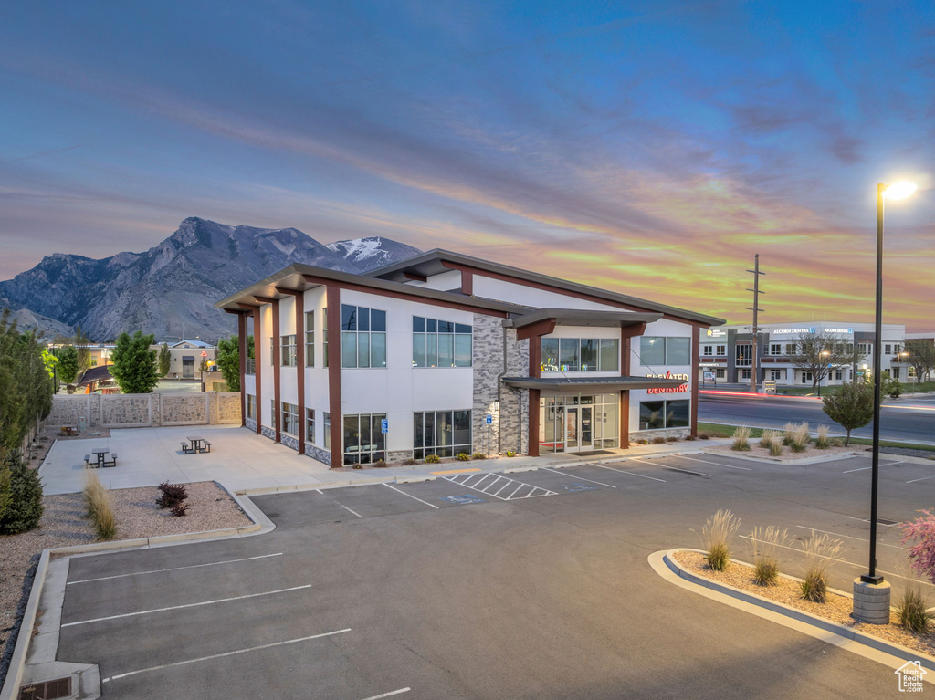 Property at dusk featuring fence, a mountain view, and uncovered parking