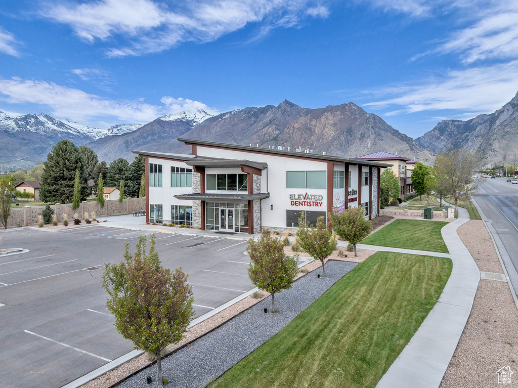 Exterior space featuring fence, uncovered parking, a mountain view, a yard, and stucco siding