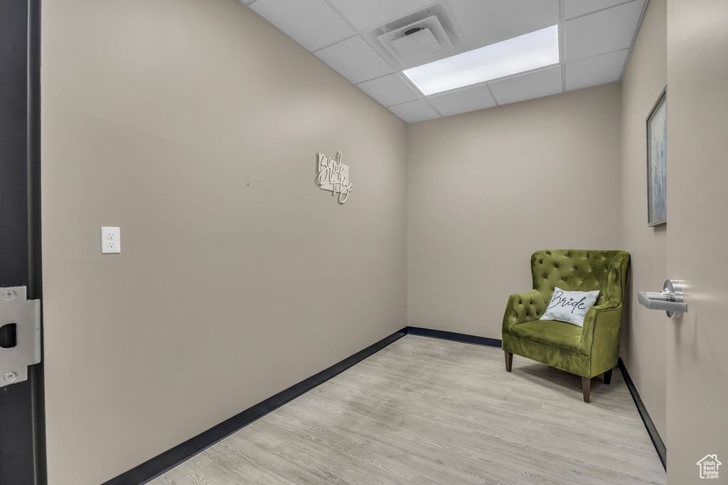 Living area featuring visible vents, a paneled ceiling, baseboards, and light wood-style floors