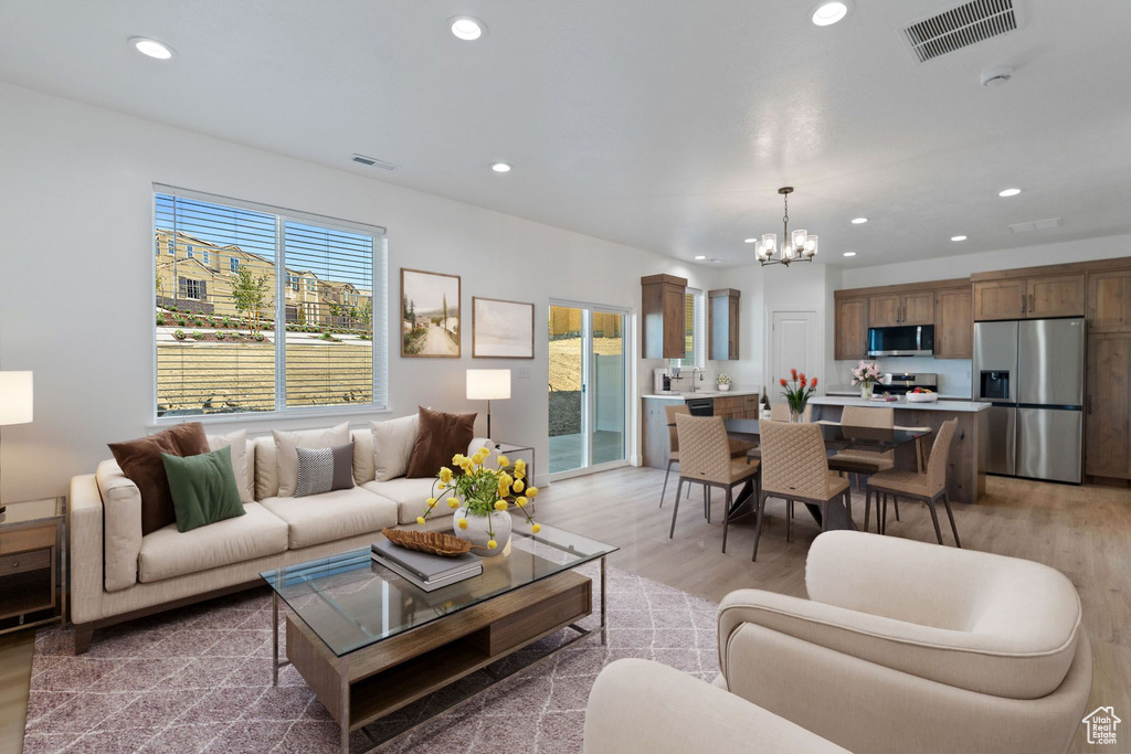 Living room with recessed lighting, a notable chandelier, visible vents, and light wood-type flooring