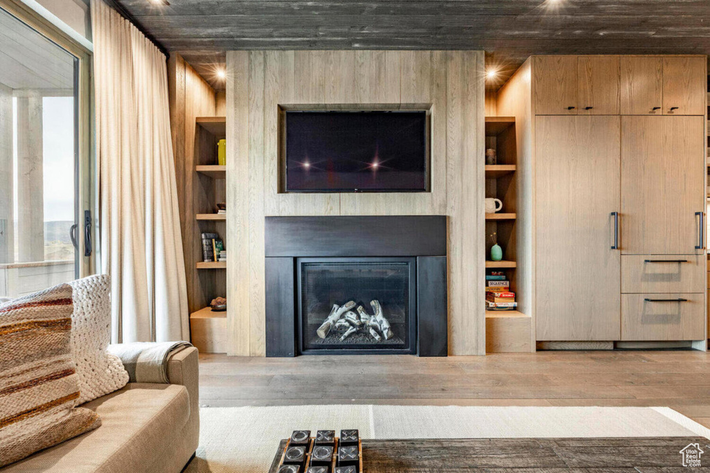 Living area with a fireplace, built in shelves, and wood finished floors