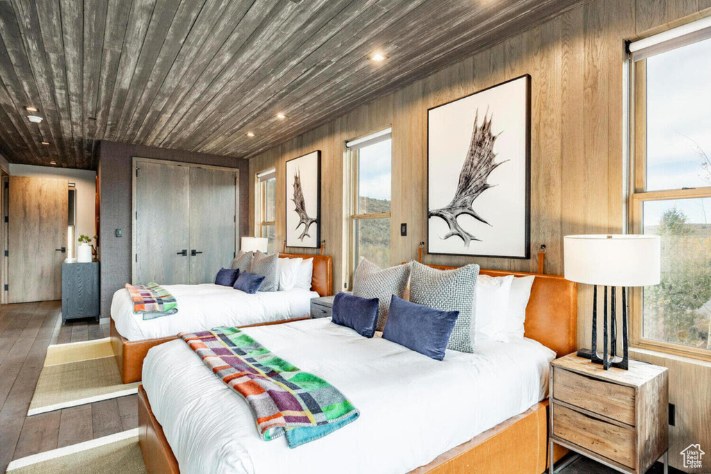Bedroom featuring wooden walls, recessed lighting, multiple windows, and wood finished floors