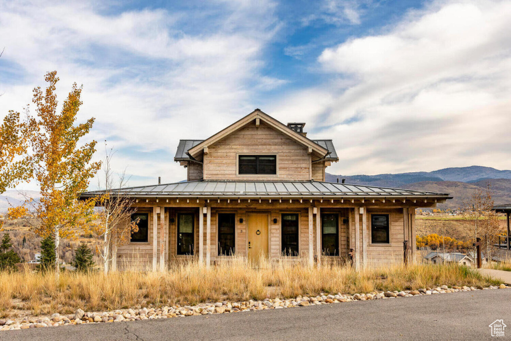 Farmhouse-style home featuring covered porch, a standing seam roof, metal roof, and a mountain view