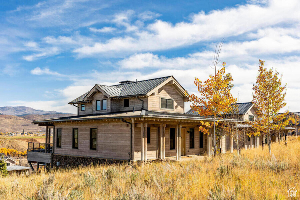 Back of property with a porch, a mountain view, a standing seam roof, and metal roof